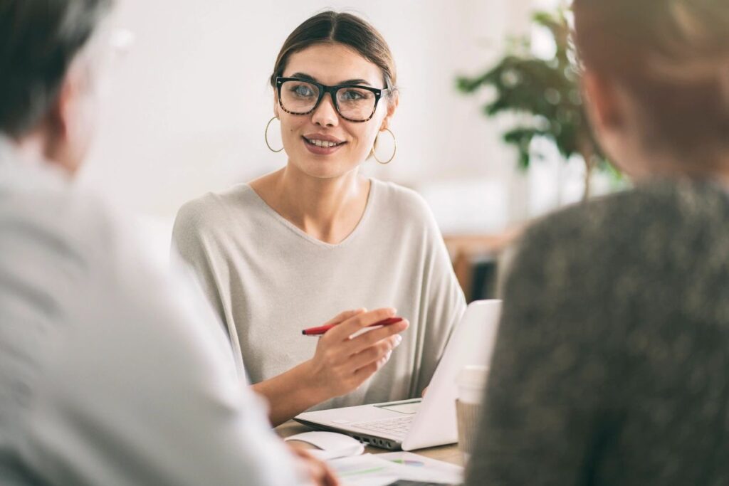 Image of woman at a desk speaking to a man and a woman